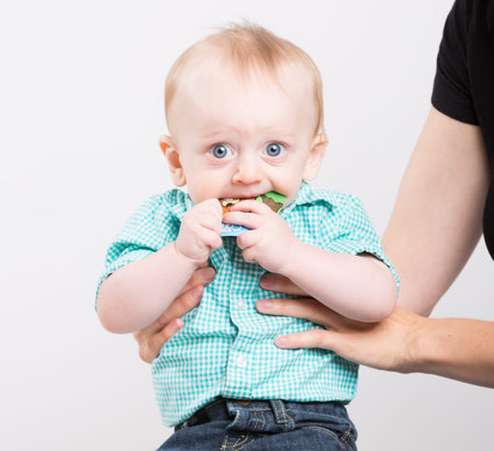 mother is grabbing her child while he chews on a cardboard tag nervous