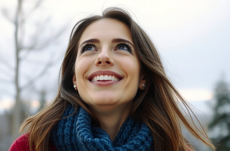 Close up portrait of beautiful young woman with blue eyes and long brown hair, wearing red sweater, blue scarf, smiling at camera, outdoorの素材