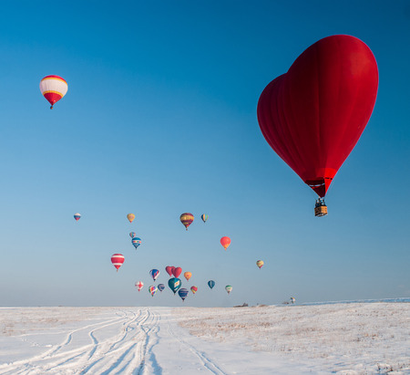 Balloon in the form of heart on snow field and the other colored balls awayの写真素材