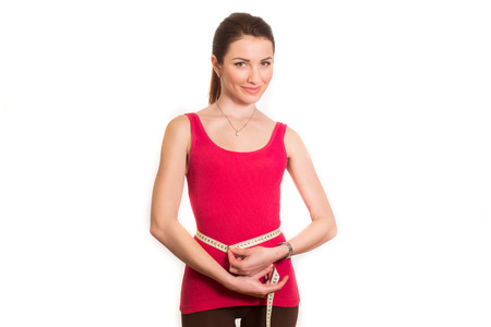 pretty fitness girl measuring her waist isolatedの写真素材