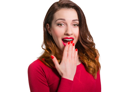 Pretty woman in red looking away in awe surprised with mouth open wide isolated on white backgroundの写真素材