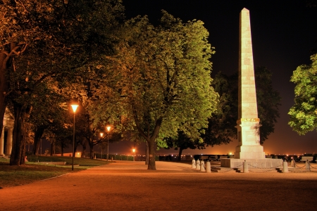Park path with illuminated obelisk at nightの写真素材