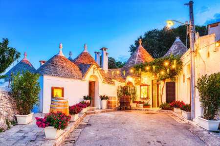 Famous Trulli Houses in Alberobello Illuminated at Dusk, Puglia, Italyの写真素材