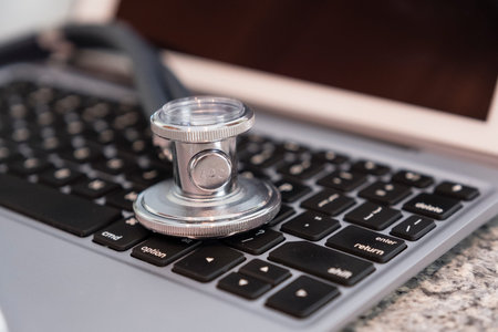 Stethoscope on keyboard countertop ready for use and data entry by medical professional