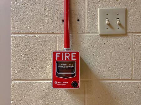 Honeywell Notifier Fire Alarm Handle Pull switch on the white wall as background for emergency case at the new factory buildingのeditorial素材