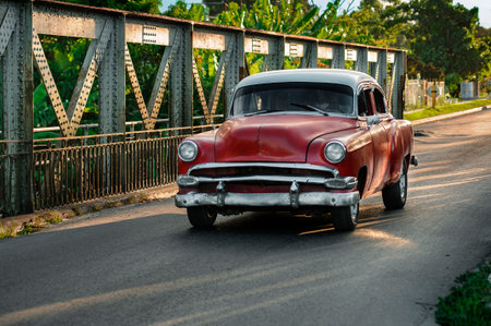 Red vintage car passing through metal bridge in Cubaの写真素材