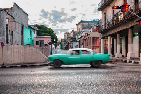 Vintage car driving through colorful Havana street in Cubaの写真素材