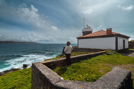 Woman enjoying ocean view near lighthouse on cloudy dayの写真素材