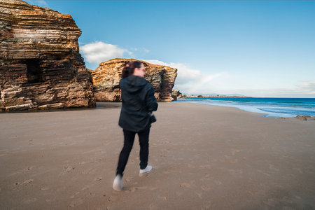 Woman walking on las catedrales beach with motion blurの写真素材