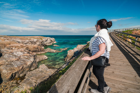 Woman admiring scenic coastal view on las catedrales beach boardwalkの写真素材