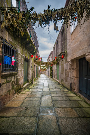 Wet cobblestone alley in old European town decorated for Christmas