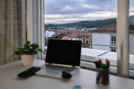 Laptop on desk with old town view through window