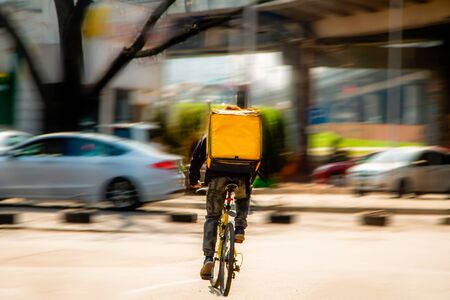 Courier on a bicycle to pick up and deliver an order from the fast food restaurant. Photo in motion. Coronavirus outbreak.の写真素材