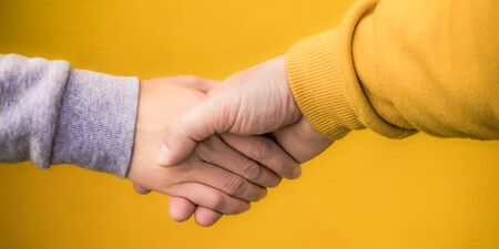 Handshake of a woman and a man in a kebabed dress on a yellow backgroundの写真素材
