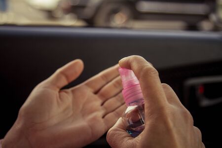A woman disinfects her palms with an antiviral alcohol product from a spray bottle with a dispenser.の写真素材