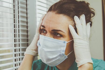 Medical professional in a surgical protective mask is tired after a shift during a coronavirus epidemic.の写真素材