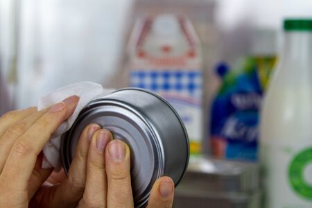 Cleaning the can after the supermarket with an alcohol-containing disinfectant napkin. Washing food during the coronavirus pandemic.の写真素材
