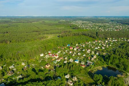 Eco-settlement among the green forest. Aerial images of houses with roofs from a height in residential areas of the suburbs. Cottage town built under the mortgage program.の写真素材