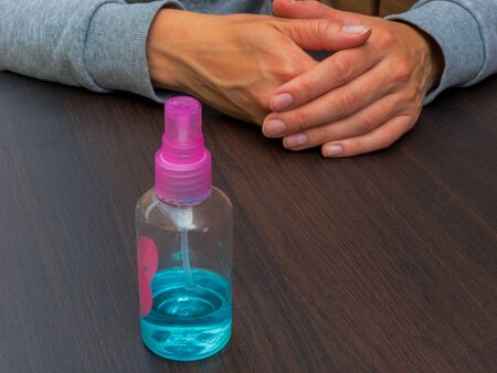 A manual sanitizer stands on the table of the summer terrace of cafe in front of a girl awaiting an order. Mitigation of quarantine measures.の写真素材