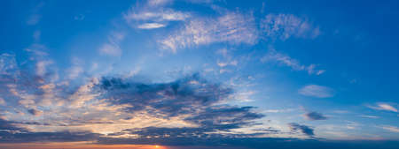 Magnificent magical panorama of blue skies at dawn with sun rays and warm cloudsの写真素材