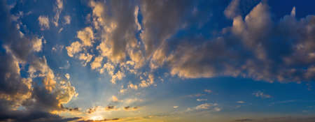 Sun Rays and warm Clouds on Magnificent magical panorama of blue skies at dawnの写真素材