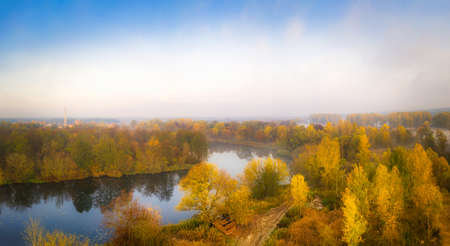 Autumn river misty landscape with clear blue sky and calm fall yellow colorの写真素材
