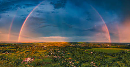 A huge double rainbow in the blue storm sky is a unique natural phenomenon after rainの写真素材