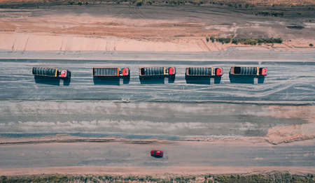 Convoy of trucks moves along asphalt road covered with sand, top viewの写真素材