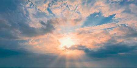 Sunny Evening. Sun at the horizon and yellow clouds on blue skyの写真素材