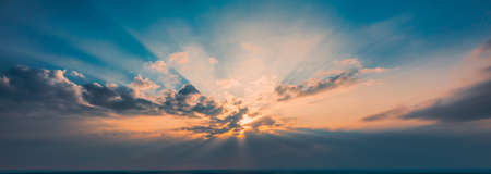Rays of the setting sun break through the clouds - wide shotの写真素材