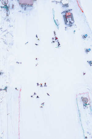 Skiers and snowboarders on a snowy slope in winter - top view shotの写真素材