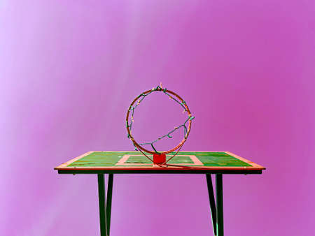 Creative advertising: a green basketball hoop with a shield on a pink sky backgroundの写真素材