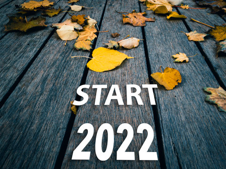 Bye 2021 inscription on a wooden autumn background with yellow leaves.の写真素材