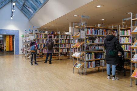 People are browsing through the shelves of the building, searching for their desired publications in the libraryのeditorial素材