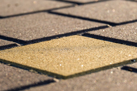 This is a detailed view of a textured pavement featuring a distinctly highlighted square section, which effectively showcases its unique patterns and vibrant colors that draw attentionの写真素材