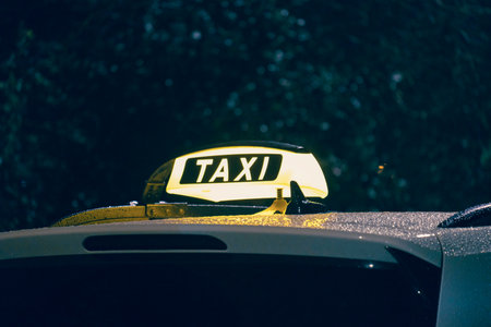 A vibrant and glowing taxi sign lights up on a rainy night, perfectly capturing the essence of urban transportation and the unique nighttime travel experience that comes with it in the cityの写真素材