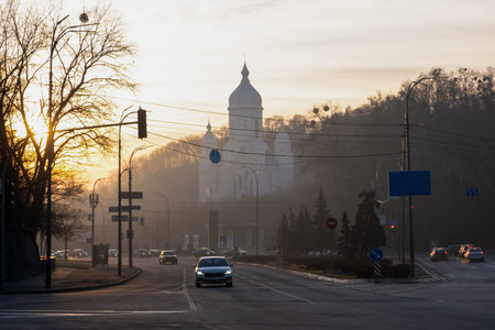 A peaceful and tranquil morning scene showcasing a misty urban landscape that includes beautiful historic architecture illuminated by the soft golden light of the rising sun in the skyの写真素材