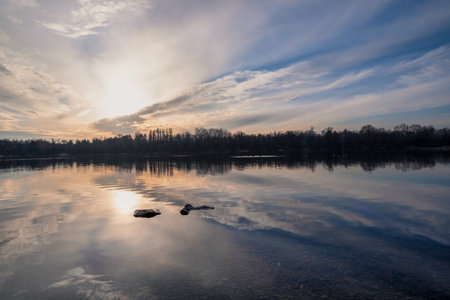 A beautifully picturesque sunset casts an array of brilliant colors over the serene and calm lake, gracefully reflecting the stunning beauty of nature and creating a truly peaceful atmosphereの写真素材