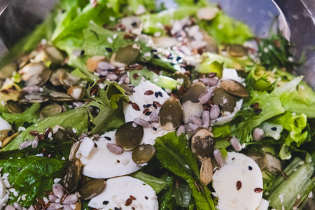 This is a vibrant and colorful salad creation that showcases an array of fresh greens, delicious mozzarella cheese, and a delightful mix of seeds to enhance both crunch and nutrition appealの写真素材