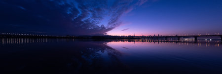A breathtaking panorama that exquisitely captures the enchanting twilight hues reflecting over a tranquil river, beautifully showcasing a serene skyline that evokes peace and calmness in natureの写真素材