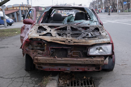 A dilapidated and rusting car is left abandoned on the roadside, vividly showcasing the profound effects of time and neglect in an urban environment, capturing both decay and historyの写真素材