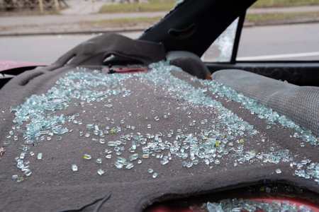 In this closeup image, we see shattered glass pieces completely scattered across a car seat, vividly illustrating the unsettling aftermath of a significant vehicle collision or breakin eventの写真素材