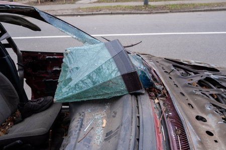 An abandoned vehicle positioned in a neglected urban environment, prominently featuring a shattered windshield and a decaying interior, highlighting the themes of urban decay and neglect in societyの写真素材