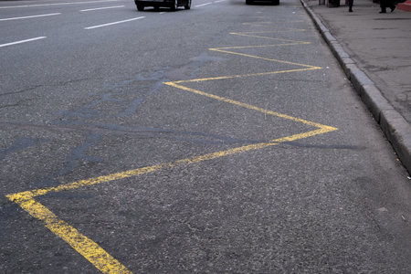 This closeup shows a zigzag pattern of bright yellow lines on a busy city street, highlighting important traffic markings that guide vehicles and supporting urban movement in the bustling metropolisの写真素材