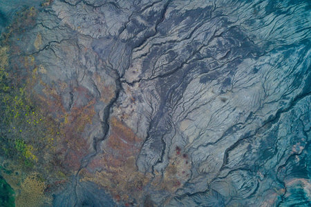 Drone view of mineral-rich terrain with cracked earth and erosion lines forming organic abstract shapesの写真素材