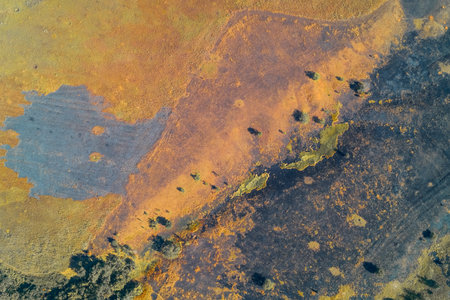 Top-down aerial photo of a highly abstract landscape with sharp contrast between black, burnt earth and orange, dry vegetation. Conceptual image of fire aftermath and environmental crisis.の写真素材