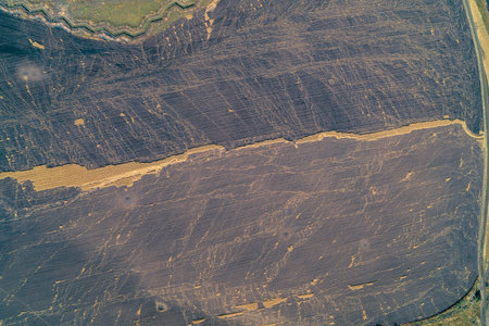 Top-down aerial photo of vast dark, possibly burnt or damaged earth, featuring a horizontal line of...