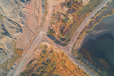 Aerial abstract composition of an industrial wasteland. Complex geometric road patterns intersect with eroded quarry textures and polluted water, illustrating severe land degradation.の写真素材