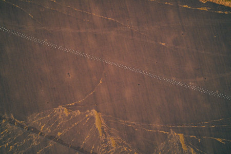 Aerial documented evidence of a military anti-tank obstacle. A straight line of Dragons Teeth (concrete tetrahedrons) in a tilled field, showing defensive fortification and military engineering.の写真素材