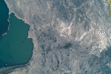 Aerial documented evidence of an ecological disaster. Shelling craters mark the surface of a toxic industrial waste tailings dam next to a polluted lake, showing environmental damage.の写真素材